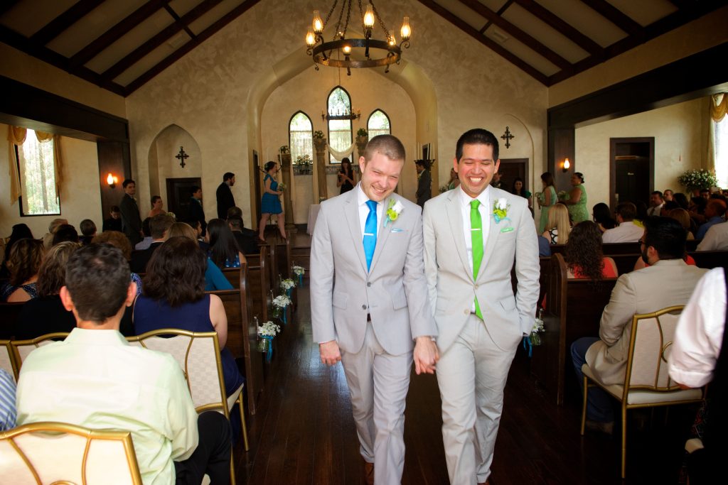 Smiling couple walking down the aisle, holding hands in the Historical Chapel in Comfort Texas